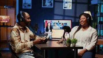 Vlogger show host and guest talking in neon lights ornate living room personal studio. Man and woman broadcasting discussion on online podcast episode using professional equipment. video