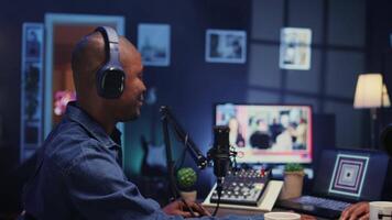 Show host recording podcast with guest, using analog mixer and professional mic in studio. Zoom out shot of man setting up audio device for live broadcast with woman, ensuring flawless sound quality video