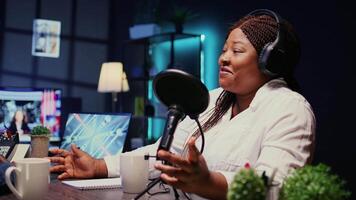 Zoom in on african american woman streaming podcast using vlogging camera during live political debate on vlog channel. Internet show presenter in dimly lit studio, close up video