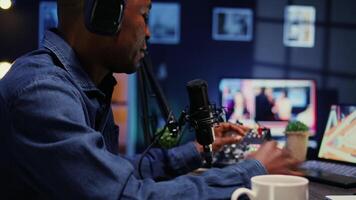 African american show host recording podcast with guest, using analog mixer and professional mic in studio. Close up shot of man setting up audio devices for live broadcast for flawless sound quality video