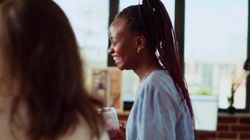 fechar acima tiro do africano americano mulher dançando por aí casa durante apartamento festa, casa convidado desfrutando animado música, fazendo dança movimentos e bebendo vinho às social encontro com dela amigos video