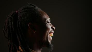 African american guy having fun on black background, laughing at jokes with his colleagues and enjoying free leisure time at the studio. Adult feeling joyful, laughs at funny memes. Handheld shot. video