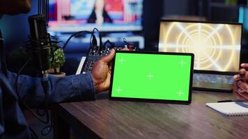 Man invited to podcast watching internet clips on green screen tablet with host in living room studio. Guest and presenter reacting to videos on mockup device during online comedy show, close up