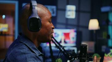 Close up shot of BIPOC host recording entertaining discussion during podcast filmed in apartment studio. Happy presenter uses professional equipment to produce comedy internet show video