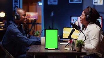 Green screen tablet in front of show host recording podcast, enjoying cup of coffee and nice conversation with guest. Mockup device in professional studio used for podcasting live session with woman video