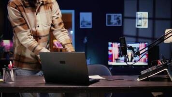 Smiling man arriving in studio, greeting audience, broadcasting live using professional equipment with high sound quality. Vlogger putting headphones on, talking with social media followers video