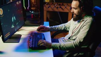 Man in neon lit apartment playing singleplayer videogame with spaceship shooting laser bullets at asteroids. Gamer using crosshair overlay to hit targets in science fiction arcade game, jib down shot video