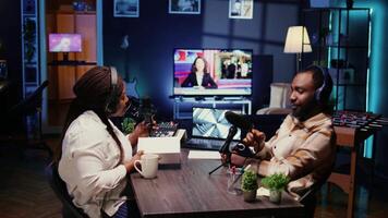 African american influencer recording podcast with guest, unboxing tech and reviewing it. Dolly in shot of cheerful man unpackaging product with host live during broadcasting session for internet show video