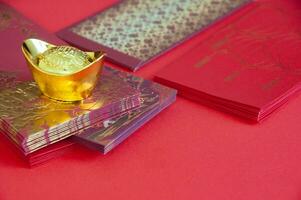 Red envelope and golden ingots on red cover background with Chinese New Year wishes photo