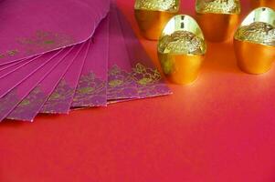 Red envelope and golden ingots on red cover background with Chinese New Year wishes. photo