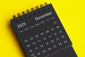 noviembre 2025 negro y blanco escritorio calendario en amarillo cubrir antecedentes. calendario concepto foto