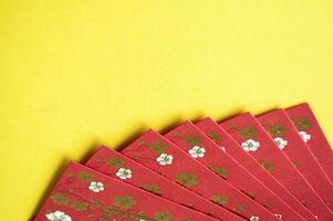 Top view of red envelopes with golden coins on yellow cover with customizable space for text photo