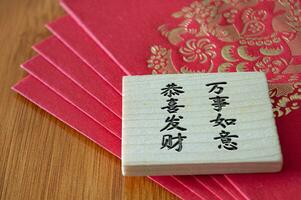 Close up view of Chinese New Year red packets with Chinese New Year wishes on wooden block photo