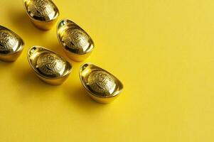 Top view of golden ingot on yellow cover background photo
