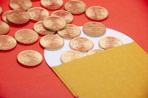 Close up of yellow envelope and golden coins on red cover background photo