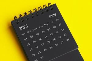 June 2025 black and white desk calendar on yellow cover background. Calendar concept photo