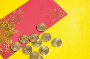 Top view of Chinese New Year red packets and golden coins on yellow cover background photo