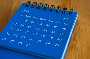 July 2024 table calendar on wooden desk. Time and calendar concept photo