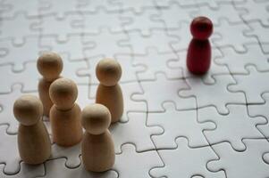 Red wooden doll leading on top of jigsaw puzzle. Leadership concept. photo