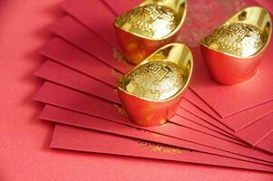 Red envelope and golden ingots on red cover background with Chinese New Year wishes photo