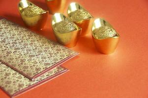Red envelope and golden ingots on red cover background with Chinese New Year wishes photo
