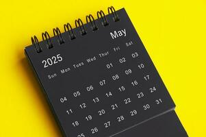 May 2025 black and white desk calendar on yellow cover background. Calendar concept photo