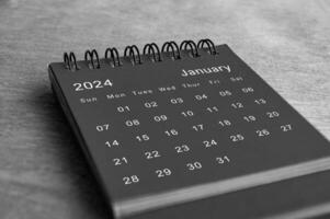 Black and white January 2024 desk calendar on wooden desk. New month concept photo