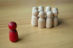 Red wooden doll separated by other dolls. Representing either leadership or isolation photo