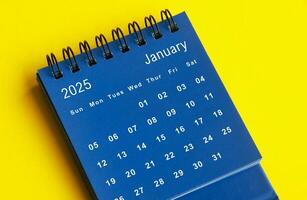 January 2025 blue desk calendar on yellow cover background. photo