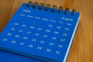 August 2024 table calendar on wooden desk. Time and calendar concept photo
