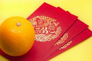 Chinese New Year red packets and orange on yellow cover background. Chinese festive season concept and copy space. photo