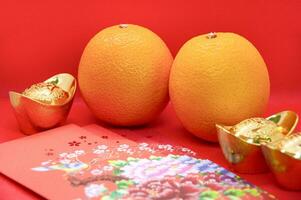 Chinese New Year decoration with oranges, colorful packets and gold ingots on red cover background. Chinese festive season concept and copy space. photo