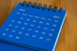 April 2024 table calendar on wooden desk. Time and calendar concept photo