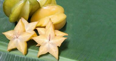 Picture of sliced star fruit placed on a banana leaf. photo