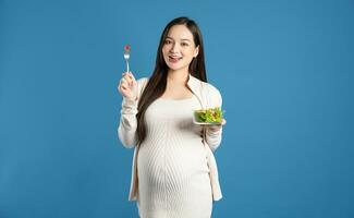 Portrait of pregnant asian woman, isolated on blue background photo