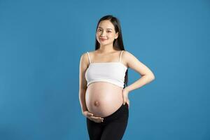 retrato de embarazada asiático mujer, aislado en azul antecedentes foto