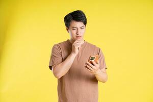 Portrait of asian man posing on yellow background photo
