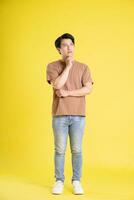 retrato de asiático hombre posando en amarillo antecedentes foto