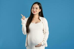 retrato de embarazada asiático mujer, aislado en azul antecedentes foto