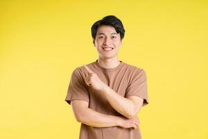 Portrait of asian man posing on yellow background photo