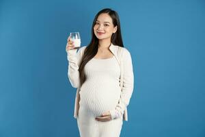 retrato de embarazada asiático mujer, aislado en azul antecedentes foto