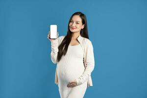 Portrait of pregnant asian woman, isolated on blue background photo