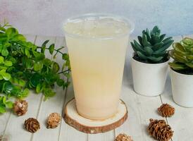 lemon ice tea or lemonade served om disposable glass isolated on wooden board top view of hong kong drink photo