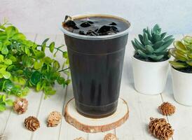 Special Grass Jelly Honey ice tea served om disposable glass isolated on wooden board top view of hong kong drink photo