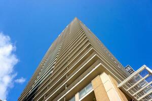 Lookup and landscape view of city buildings on bright blue sky background. photo