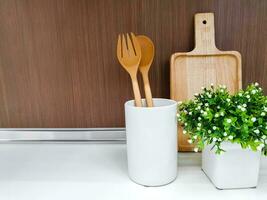 de madera batería de cocina y Decorar pequeño verde planta en blanco cerámico florero en cocina estantería y de madera pared antecedentes. foto