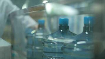 scientist worker checking the quality of water bottles on the machine conveyor line at the industrial factory. Female worker recording data at the beverages manufacturing line production. video