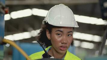 trabajadores fábrica africano mujer trabajando a pesado máquina. grupo de personas operando en frente de motor fabricado a industrial planta fábrica. inteligente industria trabajador operando. mujer sonriente y contento. video