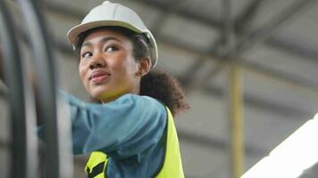 Arbeitskräfte Fabrik afrikanisch Frau Arbeiten beim schwer Maschine. Gruppe von Menschen Betriebs im Vorderseite von Motor hergestellt beim industriell Pflanze Fabrik. Clever Industrie Arbeiter Betriebs. Frau lächelnd und glücklich. video