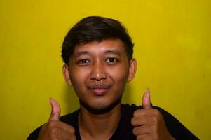 Gresik, Indonesia, 5 December 2023 - The expression of a young man who is smiling and raising both thumbs. photo